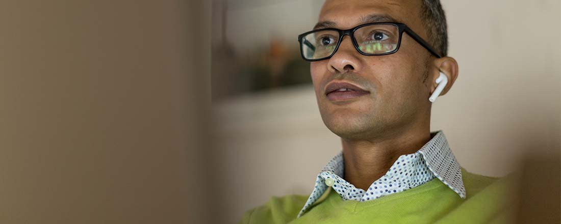 Man in glasses and fake earbuds entranced by screen